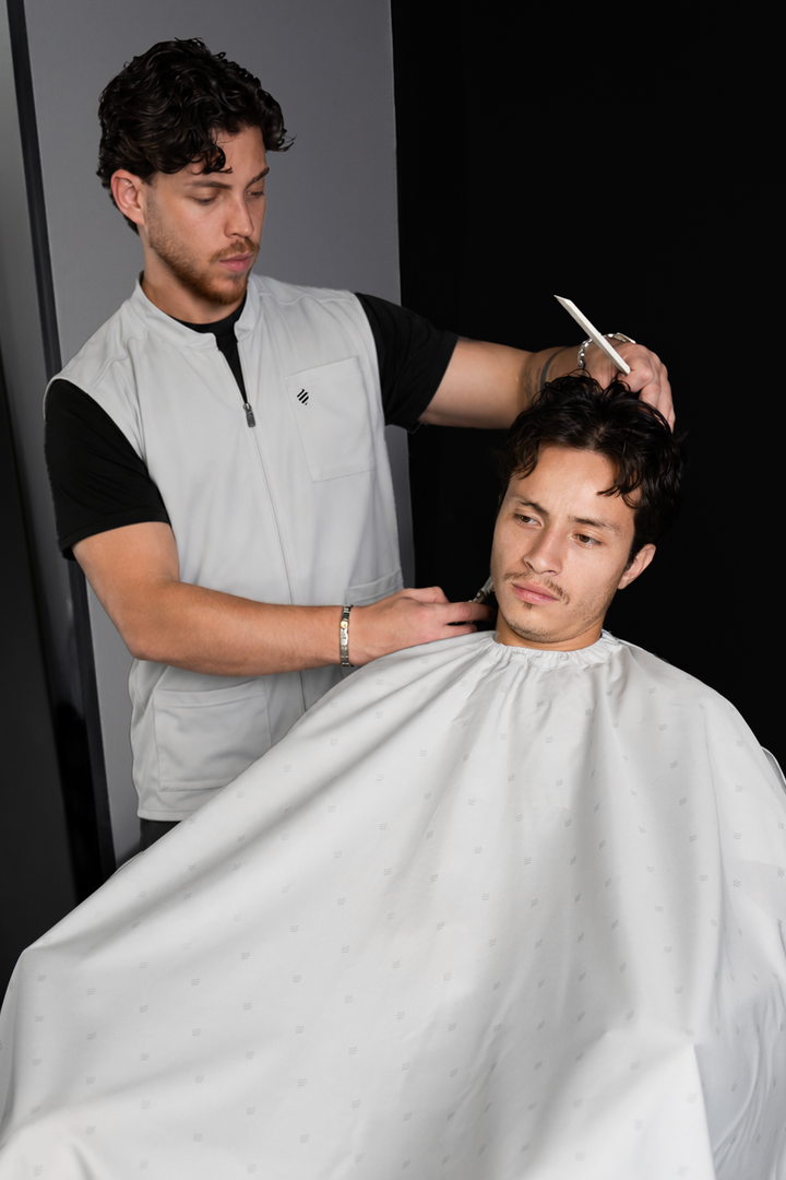Barber in the Cool Gray Barber Vest combing a client&