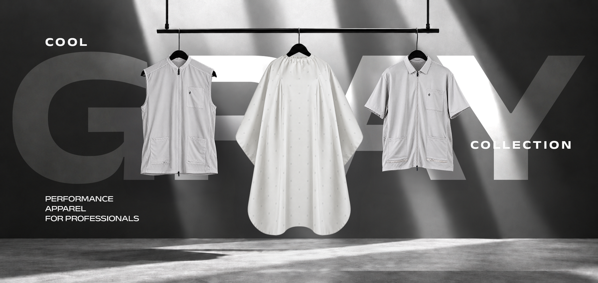 Cool Gray Collection: performance apparel for professionals. A gray barber vest, barber cape, and short-sleeve barber jacket hanging side by side on a rack.